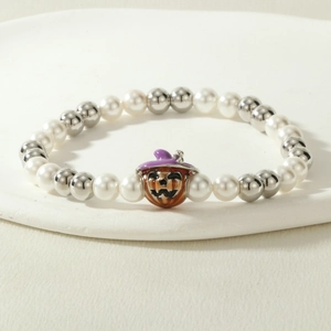 Close-up of Halloween beaded bracelet with enamel pumpkin charm and purple witch hat