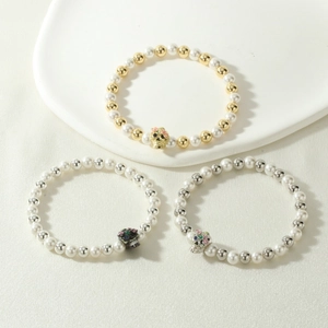 Detail of Halloween skull charm bracelets with white pearls and colorful stone inlays