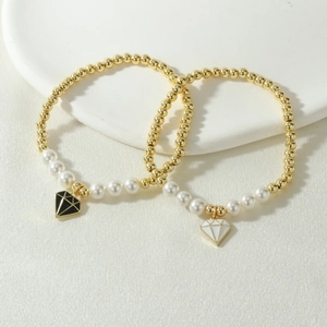 Detalle de pulseras de cuentas doradas y perlas de nácar con colgantes en forma de diamante
