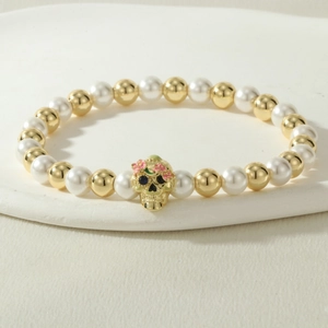 Detail of beaded bracelet with skull charm, faux pearls and golden beads on stone stand