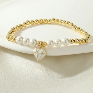 Primer plano de pulsera dorada con perlas blancas y colgante de diamante esmaltado