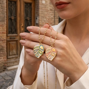 Macro detail of gold plated monstera leaf pendants with colorful enamel and zircon stones