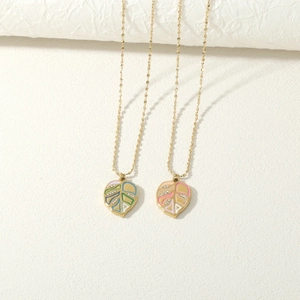 Detailed macro view of colorful enamel monstera leaf pendants with crystals and gold chain