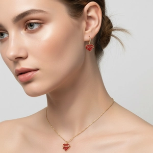 Nahaufnahme eines Models mit rotem Herzanhänger, Halskette und passenden Goldohrringen