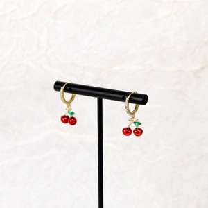 Detailed view of red cherry earrings with green leaves and sparkling zircon stones