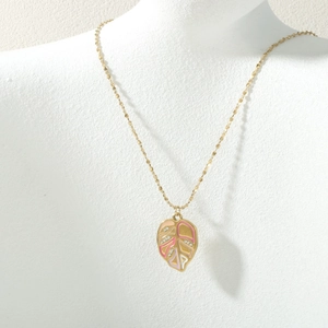 Detailed view of leaf pendant with colorful enamel and diamonds on gold chain