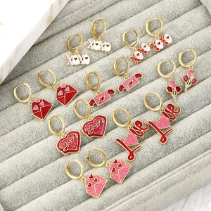 Detailaufnahme goldener Ohrringe mit Herzanhängern, XOXO-Schriftzug und Emaille-Finish