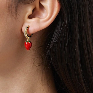 Close-up of strawberry pendant earring with gold hoop, white zircons and green leaves