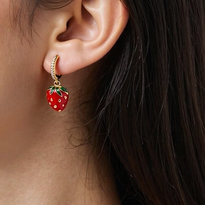 Close-up of a model wearing red strawberry hoop earrings with sparkling zircon stones