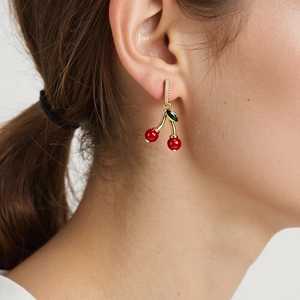 Detail of elegant cherry earrings with red fruit pendants and sparkling crystals on model