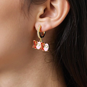 Detail von XOXO-Ohrhängern mit rotem Emaille und Pavé-Steinen auf Goldbeschichtung