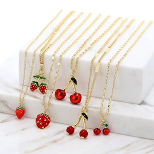 Detail of gold chain necklaces with vibrant red enamel cherry and strawberry pendants