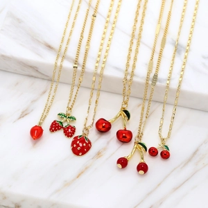 Detailed view of six gold-plated necklaces with red enamel cherry and strawberry pendants