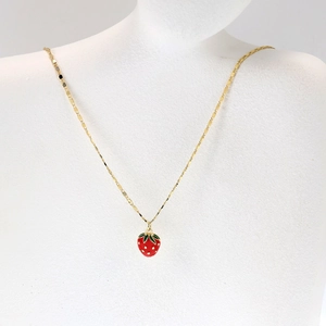 Detail of red strawberry pendant necklace with green leaves on white jewelry model