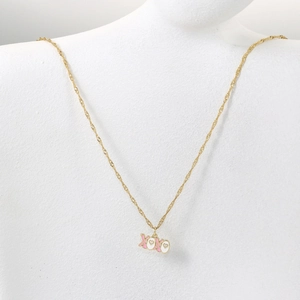 Detail der goldene XOXO Anhänger Halskette mit rosa und weißer Emaille auf einem Modell