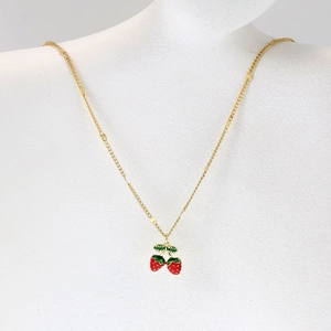 Close-up of red strawberry pendant necklace with green leaves on gold chain for women