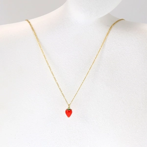 Detail of red cherry pendant with green leaf on a gold chain shown on a model bust