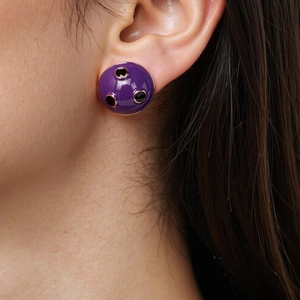 Macro shot of a purple enamel half-sphere stud earring with black dots on an ear model