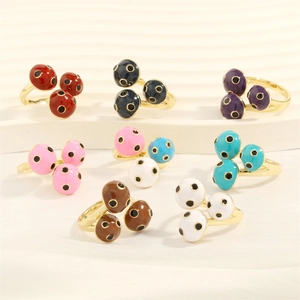 Close-up of enamel polka dot rings in various colors on a wavy white stand