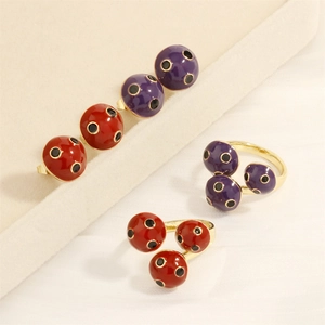 Macro detail of ladybug enamel earrings and rings set with vibrant polka dots
