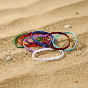 Bunte Tila-Perlenarmbänder im Bohemian-Stil, präsentiert auf feinem Strandsand