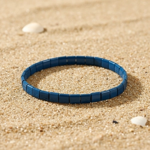 Boho Tila-Perlenarmband in Blau auf Sandhintergrund für den Sommerurlaub