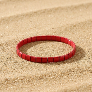 Detail eines roten Tila-Perlen-Armbands auf feinem goldenem Sandhintergrund