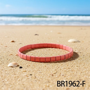 Korallenrosa TILA-Perlenarmband im Boho-Stil auf sandigem Strandhintergrund präsentiert