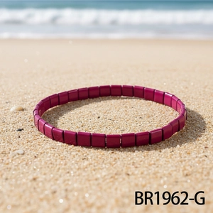 Detailaufnahme eines lila TILA-Perlenarmbands am Sandstrand für einen Boho-Sommer-Look