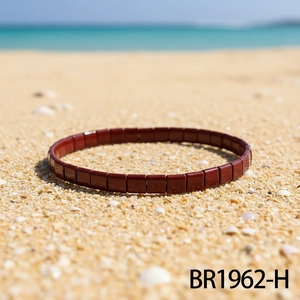 Detail eines dunkelroten Tila-Perlenarmbands mit Kacheln am warmen Sandstrand