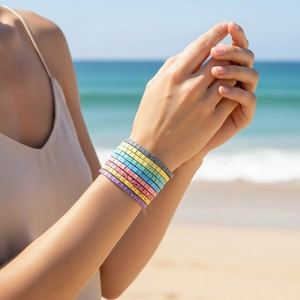 Close-up of bohemian stacked Tila bead bracelets in vibrant colors on a sunny beach