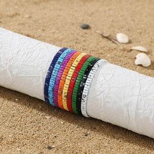 Detail of colorful bohemian handmade clay bead bracelets on a beach with shells