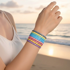 Close-up of colorful Tila bead bracelets worn on a beach during sunset for a boho look