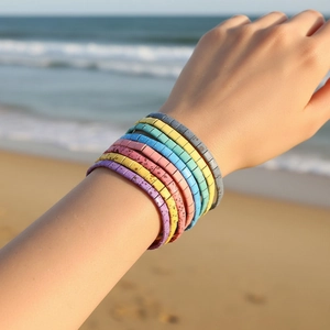 Close-up of bohemian colorful Tila bead stretch bracelets worn on a sunny beach background