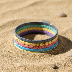 Close-up of colorful Tila bead bracelets with enamel texture on a sandy beach