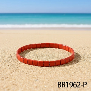Detailansicht eines roten Tila-Perlenarmbands vor einem sonnigen Strandhintergrund