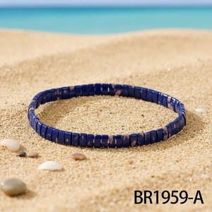 Detailed macro view of deep blue square ceramic tile beads on a sunny beach sand setting
