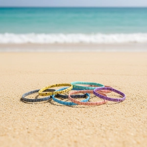 Stack of colorful Bohemian Tila bead bracelets on a sunny sandy beach by the sea