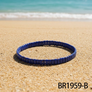Detailed close-up of blue beaded handmade bracelet on beach sand with ocean background