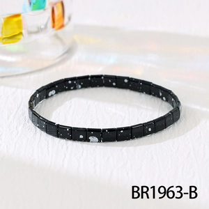 Macro shot of black Tila beads with white speckles and glossy finish on the elastic bracelet