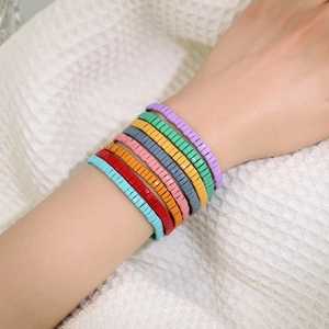 Gros plan de bracelets multicouches en perles Tila colorées portés au poignet féminin