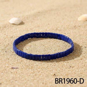 Vue détaillée du bracelet élastique en perles Tila bleu foncé sur sable de plage