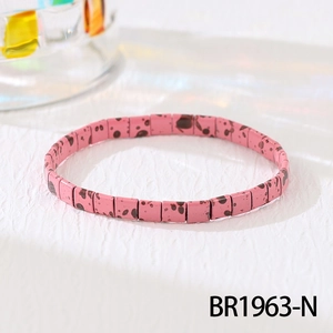Detailed macro shot of pink Tila bead bracelet with black splatter patterns on white surface