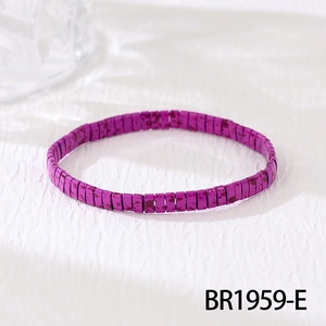 Macro shot of purple Tila bead elastic bracelet with ink splatter texture on white fabric