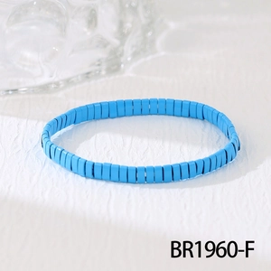 Détail d'un bracelet en perles Tila bleu ciel sur une surface blanche texturée