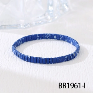 Detailopname van blauwe Tila-kralenarmband met witte spikkels op getextureerd vlak