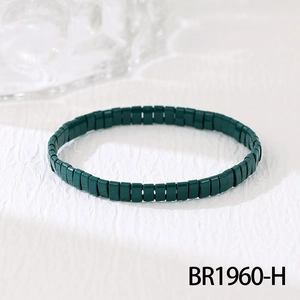 Vue macro de perles tila vert foncé sur un bracelet bohème élastique au fini brillant