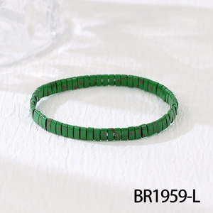 Close-up of bohemian green enamel beaded bracelet with ethnic pattern on white fabric