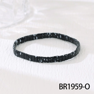 Macro shot of black bohemian beaded bracelet with white splattered patterns and elastic band