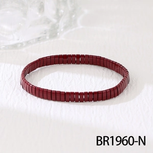 Détail d'un bracelet de perles Tila bordeaux sur un fond de tissu blanc texturé élégant